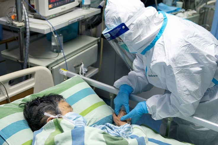 This photo taken on January 24, 2020 and released by China's Xinhua News Agency shows chief nurse Ma Jing (R) holding a patient's hand to comfort her in the ICU (intensive care unit) of Zhongnan Hospital of Wuhan University in Wuhan