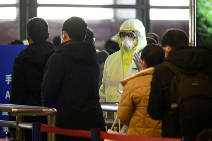 A medical worker wearing protective clothing monitors rail passengers arriving in Shanghai