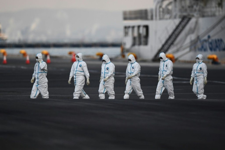 Workers in protective suits walk from the Diamond Princess cruise ship