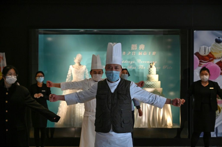 Hotel workers wearing protective face masks exercise in the lobby of the Marco Polo Hotel in Wuhan, one of the few that didn't close its doors
