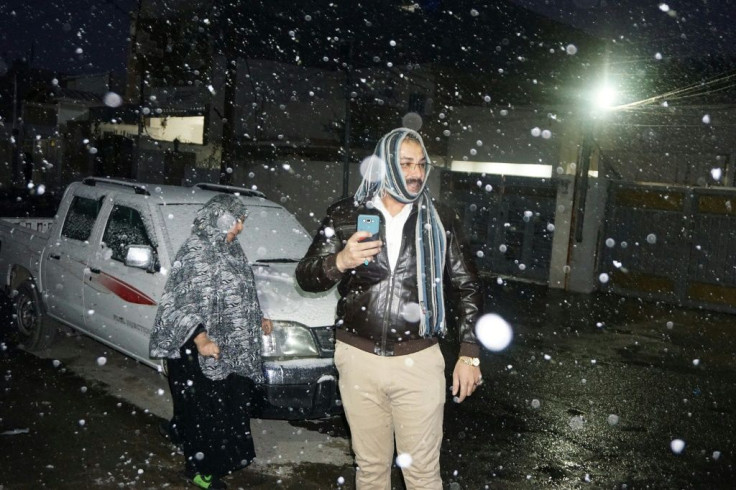 An Iraqi man snaps pictures of the ultra-rare snowfall in Baghdad, a city where summer temperatures can hit 51 degrees Celsius (124 degrees Fahrenheit)
