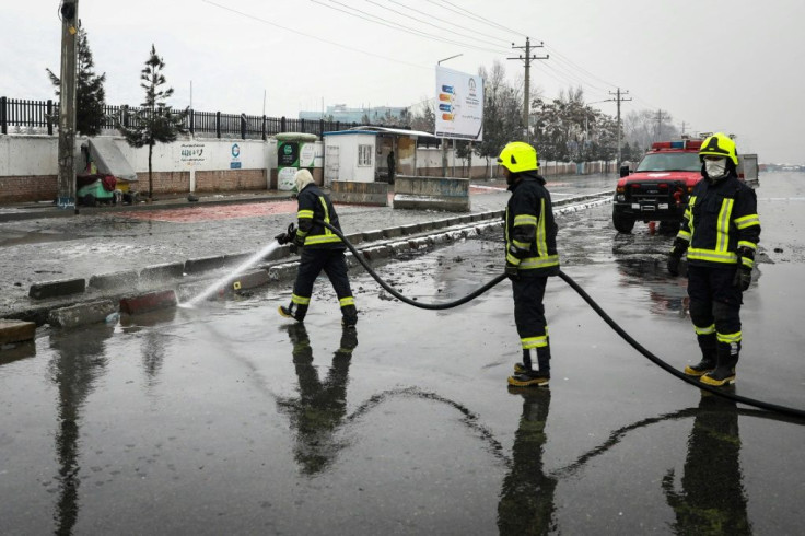 Firefighters wash part of a road following the suicide attack near the Marshal Fahim Military Academy base in Kabul