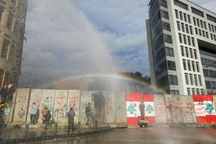 Lebanese anti-riot police fire tear gas and water cannons to try to prevent protesters scaling the blast walls around parliament
