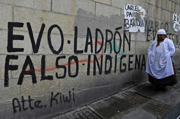 An Aymara indigenous woman walks past graffiti reading "Evo - thief, fake indigenous person", referring to Bolivia's leftist former president Evo Morales -- he is still a polarizing figure
