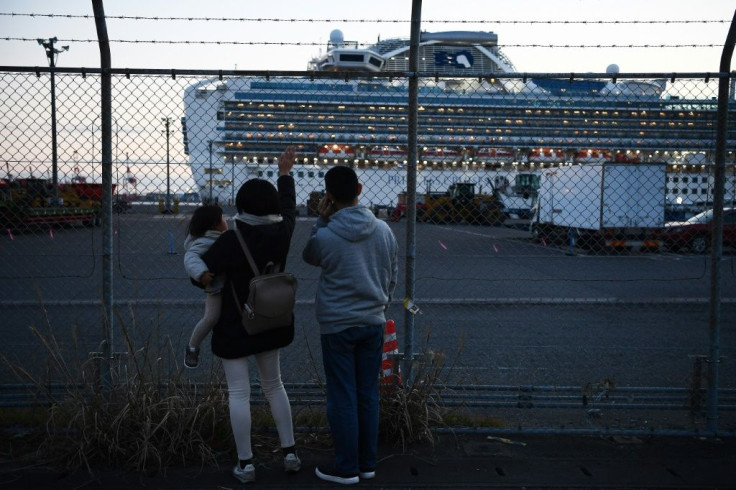 Relatives of passengers wave at those quarantined aboard ship