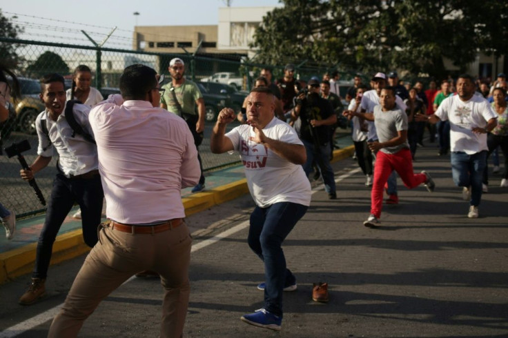 A supporter of Venezuelan President Nicolas Maduro (C) confronts a reporter (2nd L) as Venezuelan opposition leader Juan Guaido arrived home in Caracas
