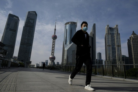 A man wearing a protective face mask walks on an overpass in Shanghai's Lujiazui financial district as officials announce the postponement of the April 19 Formula One Grand Prix