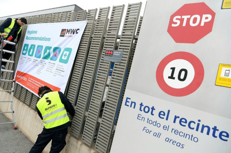 Workers install a banner with hygiene recommendations outside the Mobile World Congress venue