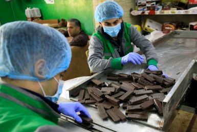 Workers at al-Arees sweets factory in Gaza City sort a batch of chocolate-covered biscuits