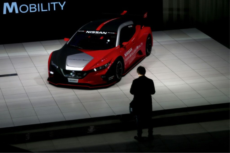A man stands next to a Nissan Leaf Niaki RC car at a Nissan showroom in Yokohama