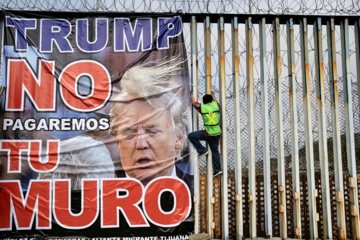 A protestor against the  wall on the US-Mexico frontier hangs a banner reading "Trump we will not pay for your wall" at Playas de Tijuana, Mexico, on February 2, 2020