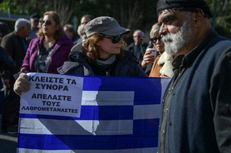 A woman holds a Greek flag and a placard reading "Close the borders, Deport the illegal migrants" during a demonstration in Athens on February 13 against the government's plans to build new migrant camps