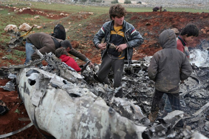 Syrians inspect the wreckage of a regime military helicopter after it was brought down over western Aleppo province