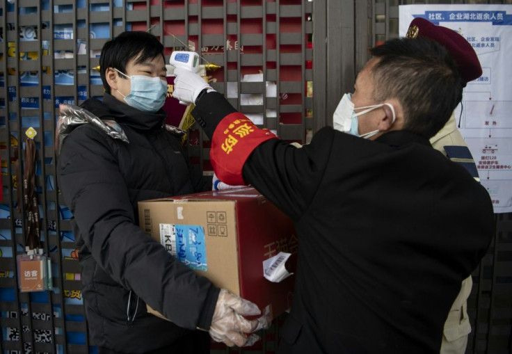 A security guard checks a man's temperature at the entrance to an apartment building in Hangzhou