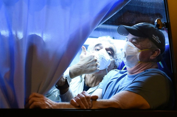 An American passenger from the Diamond Princess gives a thumbs up to reporters at Haneda Airport in Tokyo before boarding a chartered flight home. Officials said 14 passengers on  one flight had tested positive for the coronavirus