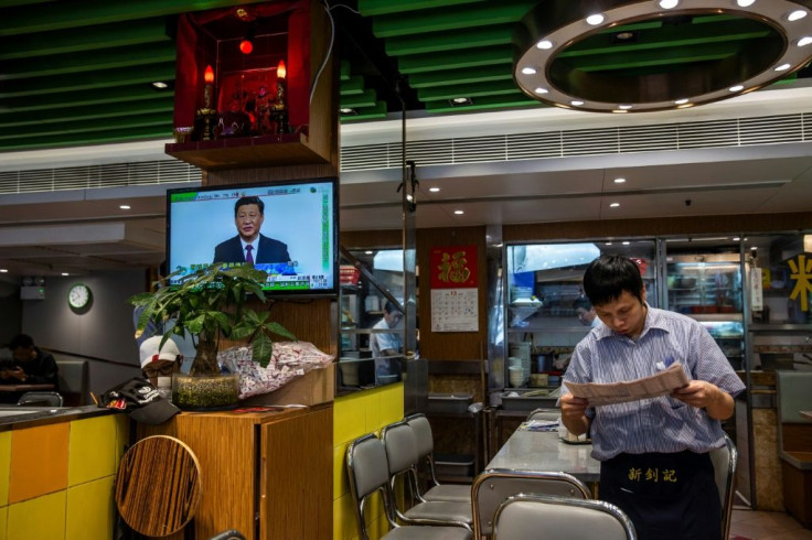 A waiter reads the newspaper as a live broadcast of Chinese President Xi Jinping shows on the television at a Hong Kong eatery in December 2019
