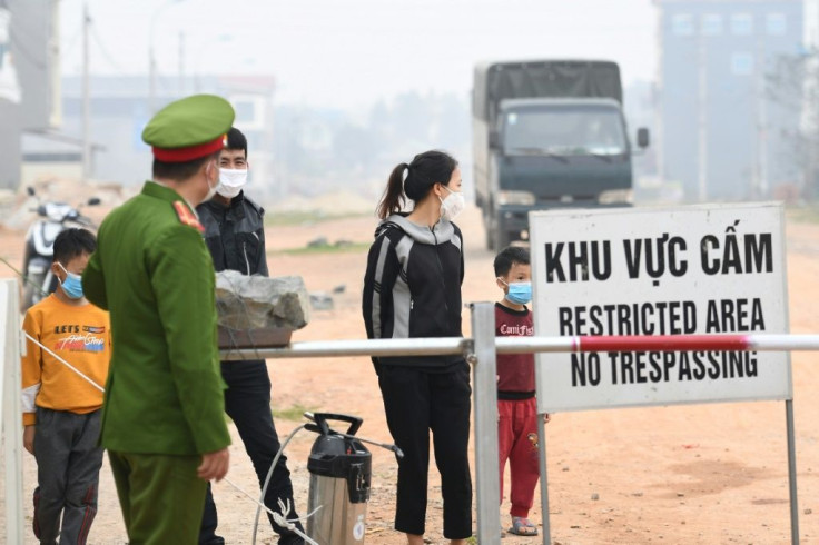 Residents stand behind a quarantine checkpoint in the Son Loi commune in Vinh Phuc province in Vietnam