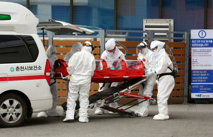 Medical workers wearing protective gear carry a patient infected with coronavirus to hospital in Chuncheon