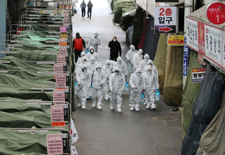 Market workers wearing protective gear spray disinfectant at a market in the southeastern city of Daegu