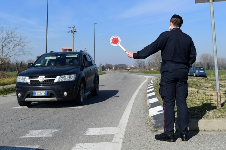 An Italian Carabinieri stops a car at a checkpoint near the small town of Castiglione d'Adda, southeast of Milan, as authorities ramp up efforts to prevent the outbreak spreading