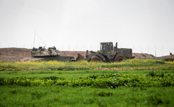 An Israeli tank and a bulldozer are seen along the border fence between Israel and the Gaza Strip where the army says troops shot dead a Palestinian suspected of placing a bomb near the barrier