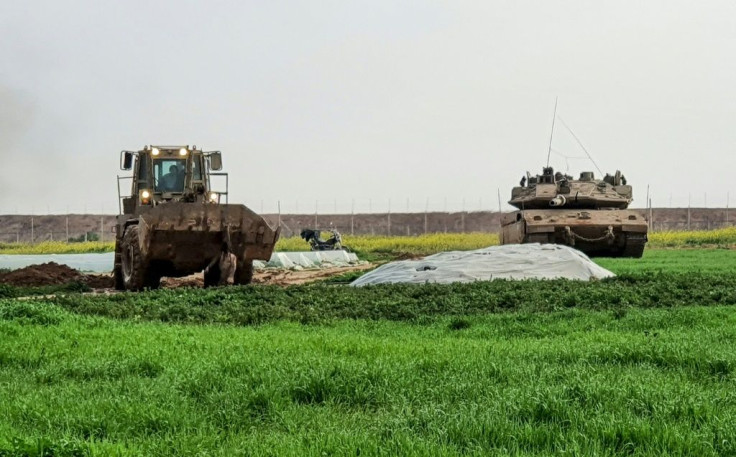 This picture taken with a mobile phone shows an Israeli bulldozer carrying the body of a Palestinian shot dead by Israeli forces after he was suspected of placing a bomb along the Gaza-Israel border