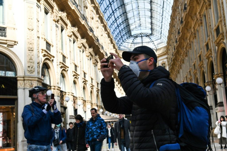 A man wearing a protective facemask takes pictures at the Gallery Vittorio Emanuele II in Milan on Monday