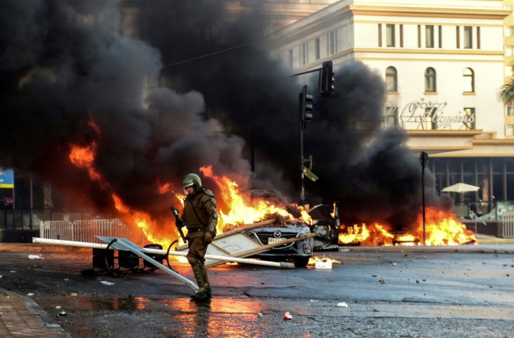 A policeman is seen near torched cars during a protest Sunday against Chilean President Sebastian Pinera's government in music festival venue Vina del Mar