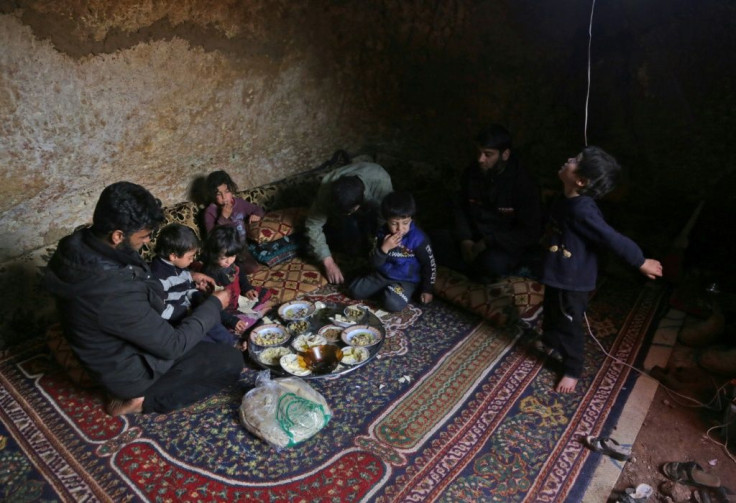 Darra lays down a large carpet for the family to share a frugal meal on the bare earth of the underground shelter