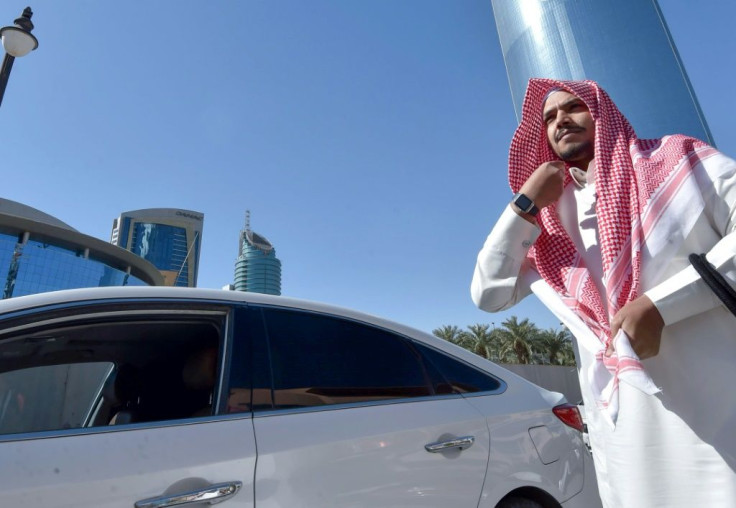 Saudi taxi driver Hussein adjusts his traditional "shemagh" head cover before getting into his car to start the day working for Uber