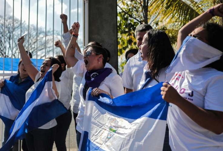 Opposition demonstrators shout slogans as they wave Nicaraguan flags during a protest outside the Divina Misericordia church in Managua