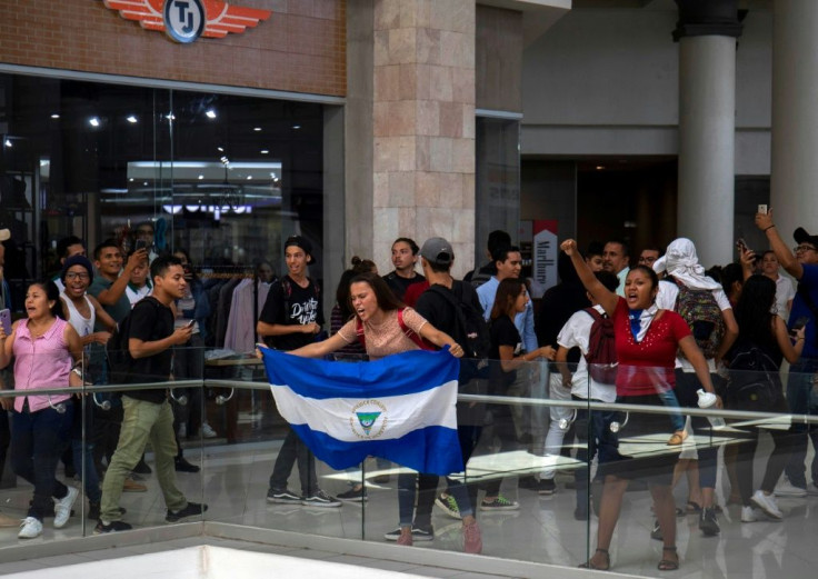 Opposition protesters with a Nicaraguan flag face off against riot police inside the Metrocentro Shopping Mall in downtown Managua