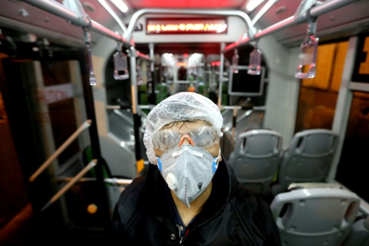 A city council worker in protective clothing disinfects a bus in Tehran as part of government efforts to control a novel coronavirus outbreak that has now killed 19 people