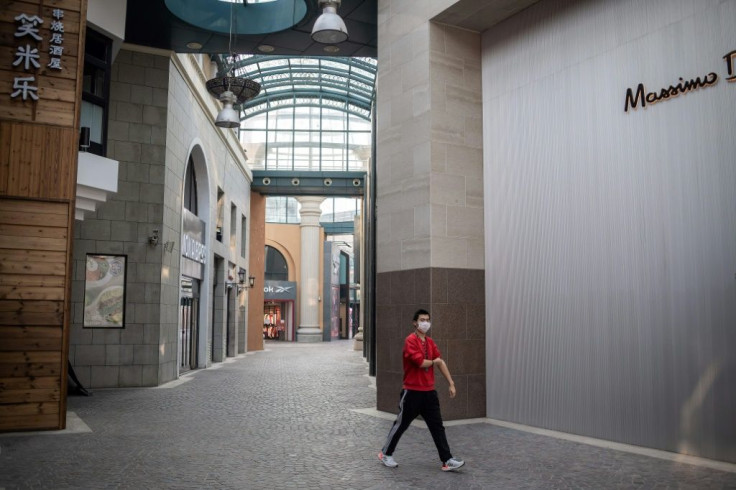 A man wearing a protective facemask, as a preventative measure against the COVID-19 coronavirus, walks through a deserted shopping mall in Beijing