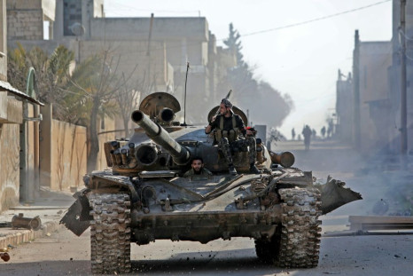 Turkey-backed Syrian fighters ride a tank in the town of Saraqib in the eastern part of the Idlib province in northwestern Syria