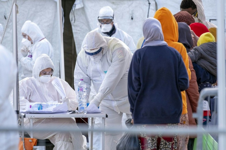 Italian Red Cross' agents wearing protective suits register migrants rescued in the Mediterranean as they disembark from the Sea Watch NGO's ship in the port of Messina, Sicily