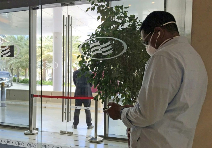 A mask-clad man uses his mobile phone while standing at the entrance of the Crowne Plaza hotel in Yas Island Abu Dhabi, one of the hotels in lockdown