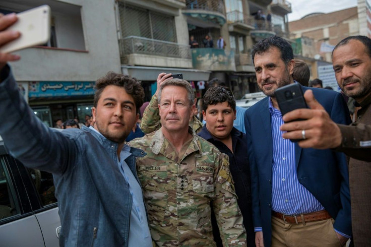 Afghan men take selfies with Commander of US and NATO forces in Afghanistan General Austin Scott Miller (2L), and Afghanistan's acting Defense Minister Asadullah Khalid (2R) as a ceasefire held between US and government forces and the Taliban
