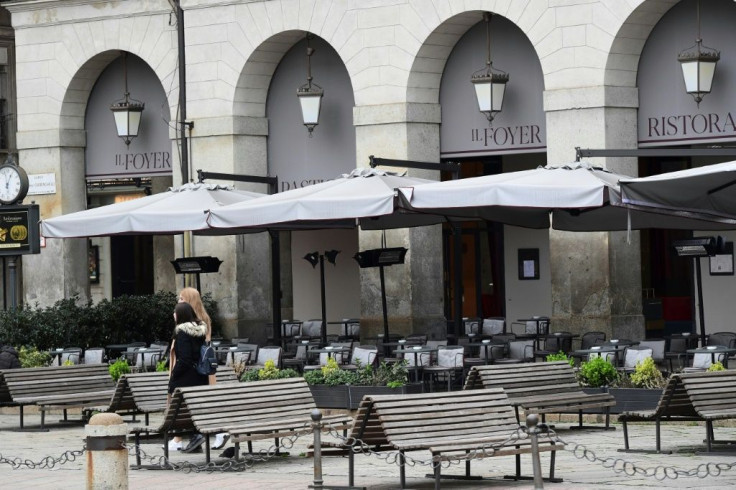 Two woman walk past deserted restaurants and a near empty Piazza della Scala on February 29, 2020 in the center of Milan