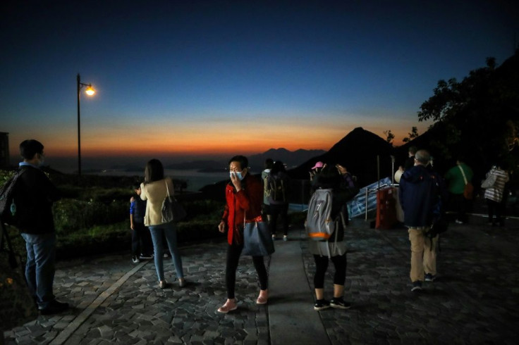 People wearing face masks as a precautionary measure against the spread of the novel coronavirus watch the sunset in Hong Kong on February 29