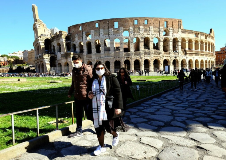 Tourists wearing protective masks visit the Colosseum in Rome as the coronavirus looks set to push the badly hit economy into recession