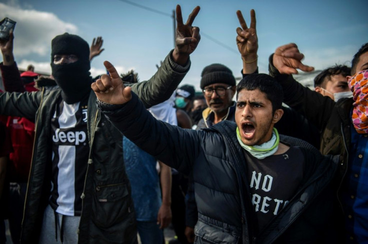 Migrants and refugees clashed with police and waved signs that said "we are not prisoners"