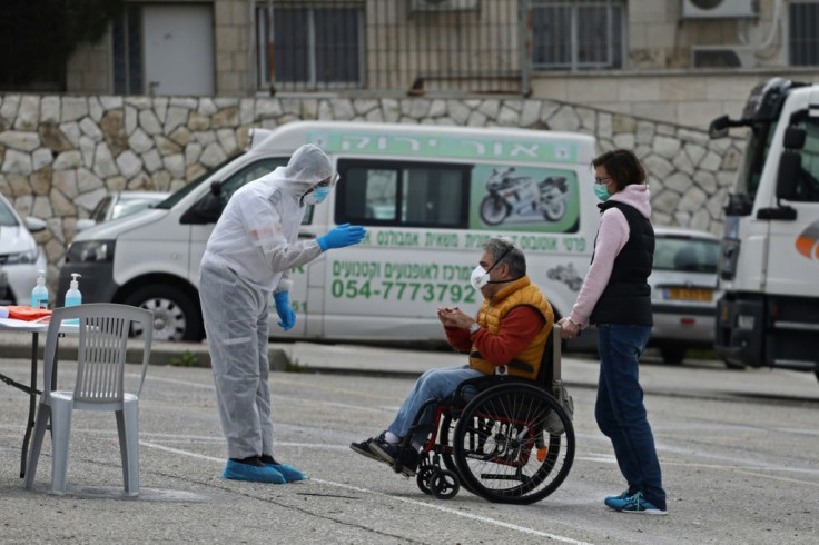 Israelis wearing protective masks vote at one of the special polling station erected for the 5,600 voters under quarantine