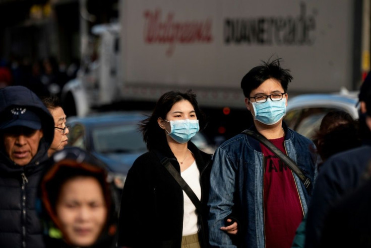 People wear face masks as they walk down a street in Flushing area of Queens on March 2, 2020 in New York City