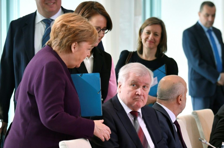 German Chancellor Angela Merkel (L) reaches out to try and shake hands with German Interior Minister Horst Seehofer