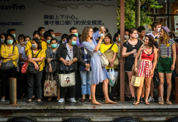 Foreign tourists take pictures next to Thai commuters with face masks as they wait for a canal boat in BangkokA Thai man has died from complications doctors say were due to the deadly coronavirus, though health officials were reluctant on March 2 to concl