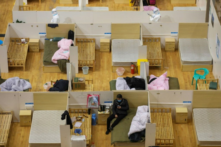 Medical workers (top) walk past empty beds at a makeshift hospital in a stadium in Wuhan. A top official hinted that the quarantine of Hubei could soon be lifted