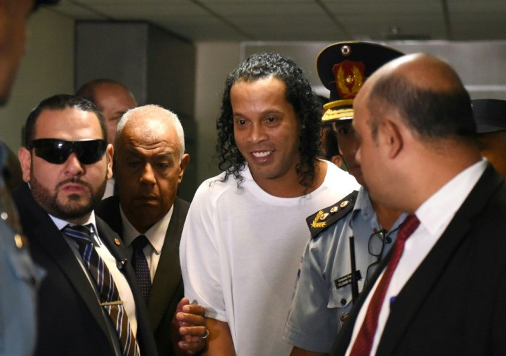 Retired Brazilian football star Ronaldinho (C) has been charged in Paraguay with using a public document with false content