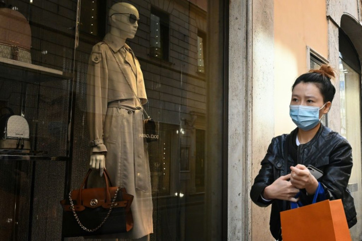 A woman wearing a masks walks past shops in Via Condotti in central Rome as the coronavirus death toll nears 200, the highest outside China