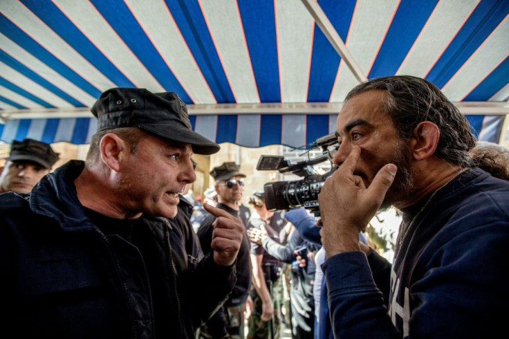 A cameraman speaks with a Cyprus police officer during the protest in the divided capital Nicosia